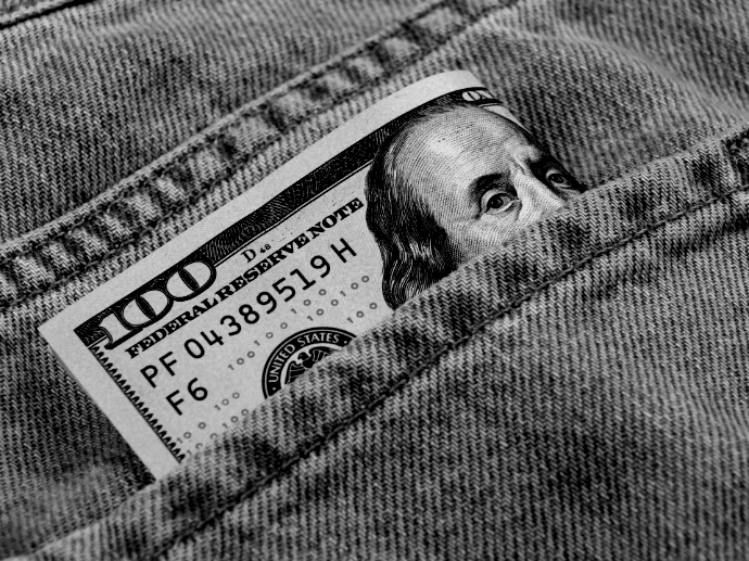 a hundred dollar bill sticking out of the back pocket of a pair of jeans